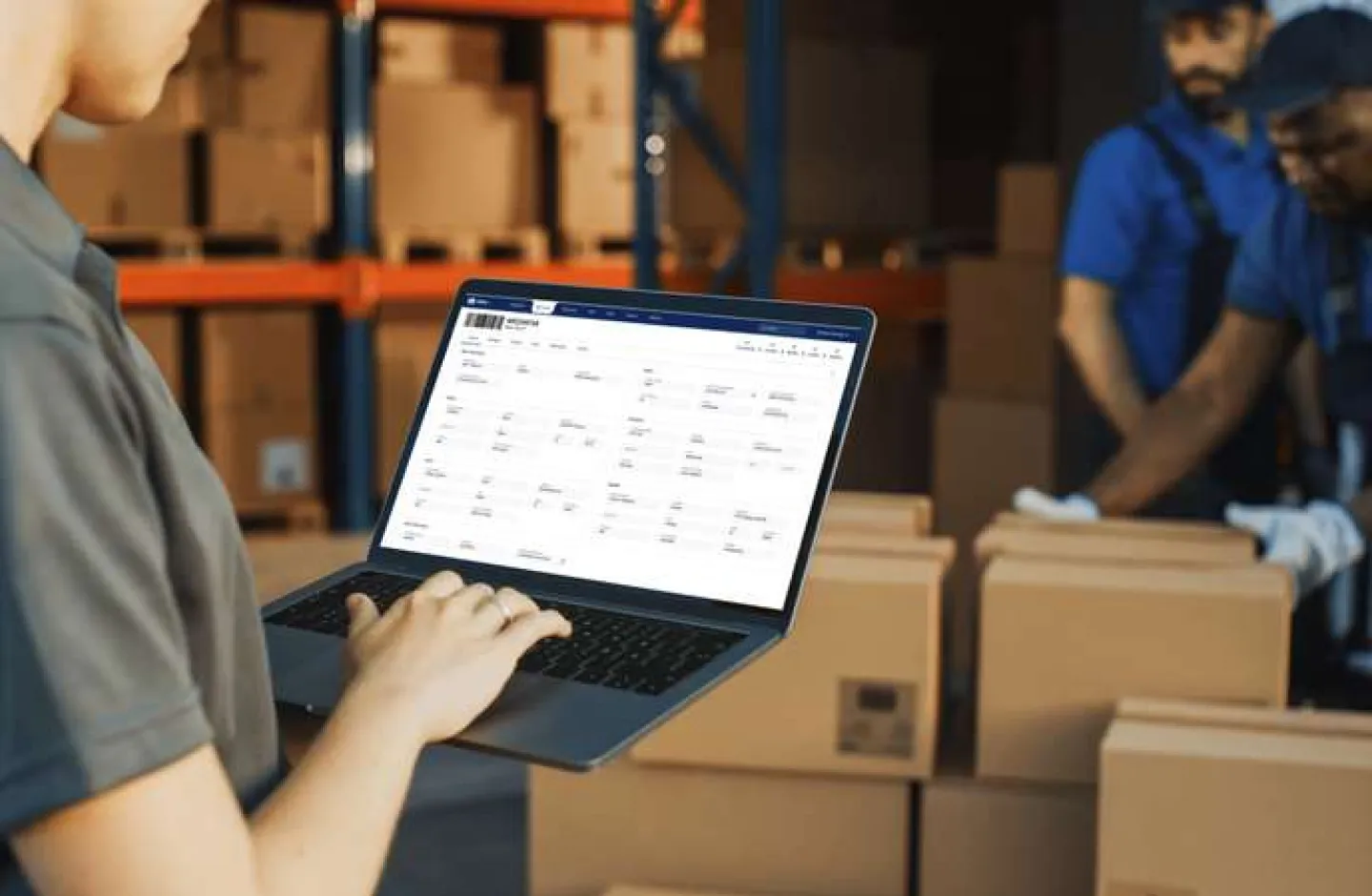 A warehouse manager on a laptop using a WMS to improve efficiency.